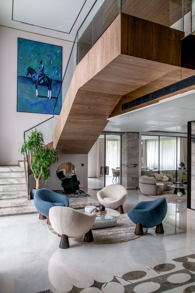 Spacious luxury living room featuring modern furniture and unique artwork under a floating staircase.