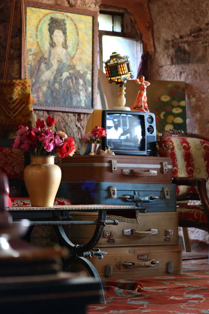 Vintage Istanbul cafe with nostalgic decor, featuring stacked suitcases and floral arrangements.